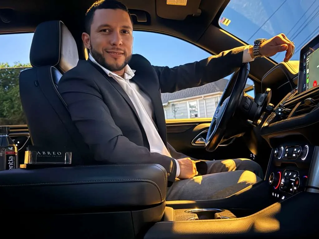 Abreo Prestige Travel founder and chauffeur Daniel Abreo beside a luxury vehicle